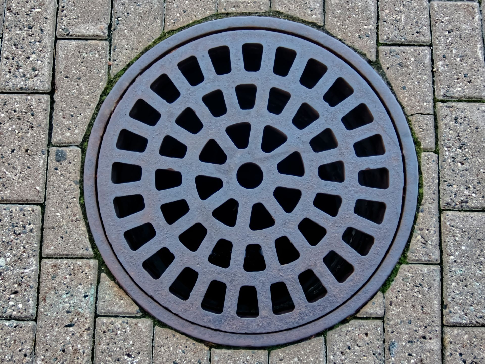 a manhole cover on a brick sidewalk